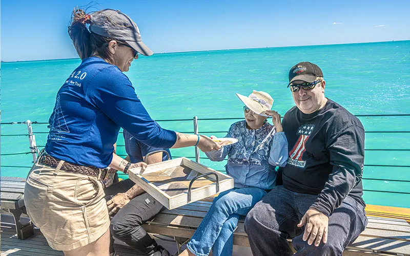 A crew member handing food to customers on a Christmas Day Brunch Cruise in Key West on Schooner America 2.0