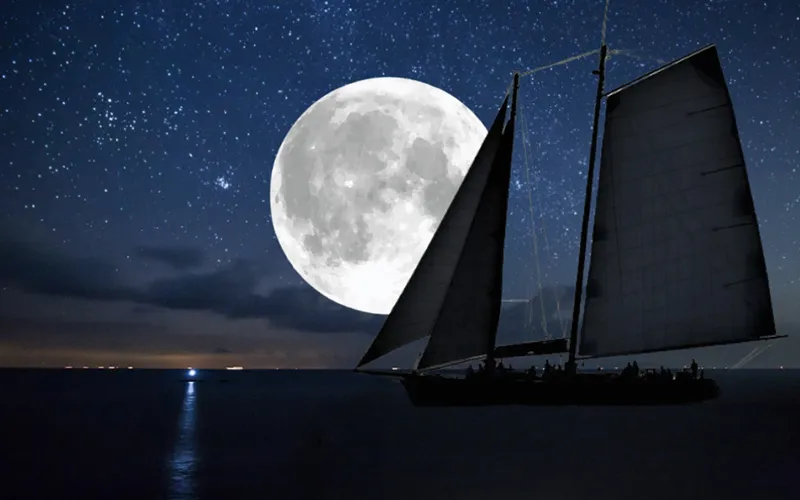 Schooner America 2.0 sailing at night under a Full Moon