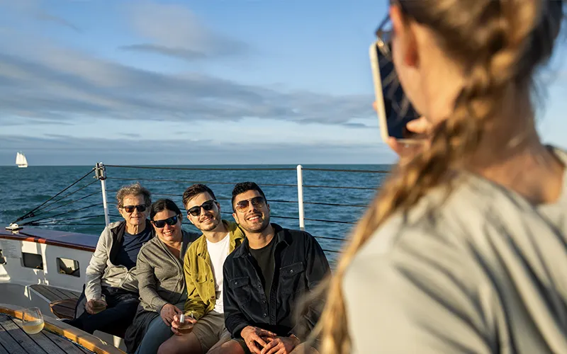 Crew member taking a photo of smiling customers on Schooner America 2.0 in Key West
